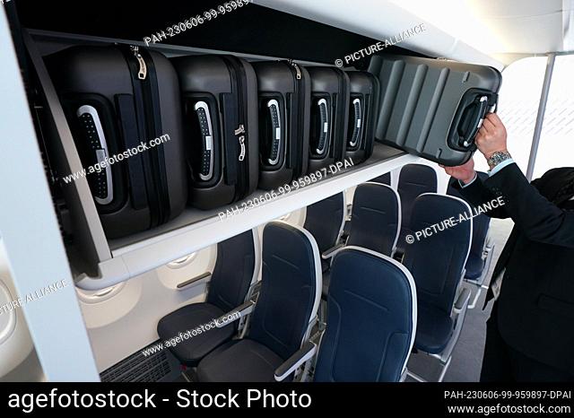 06 June 2023, Hamburg: An employee pulls a suitcase from the new luggage rack of a Boeing 737 at the booth of aircraft manufacturer Boeing at the Aircraft...