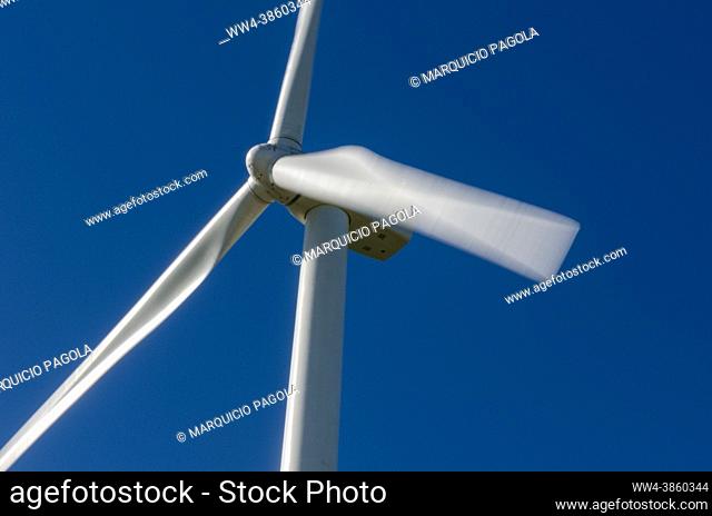 Close-up of a wind turbine turning at full power, under a completely blue and cloudless sky