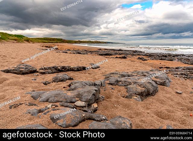 Dark clouds and large stones, seen at Cocklawburn Beach near Berwick-upon-Tweed in Northumberland, England, UK