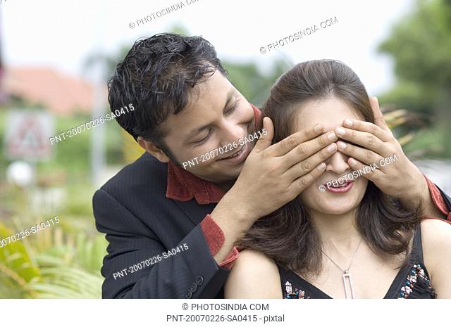 Young man covering a young woman''s eyes