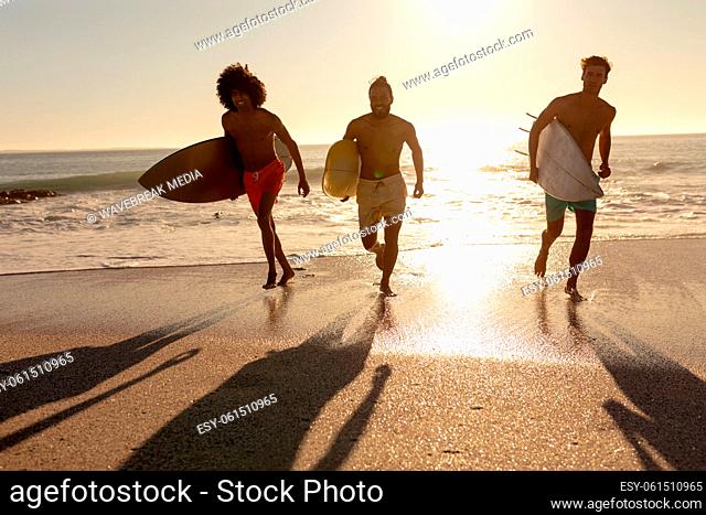 Young mixed race men holding surf boards on beach
