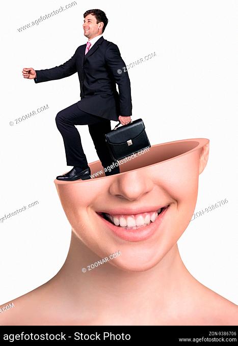 Businaessman with briefcase goes out from open woman's head isolated on white