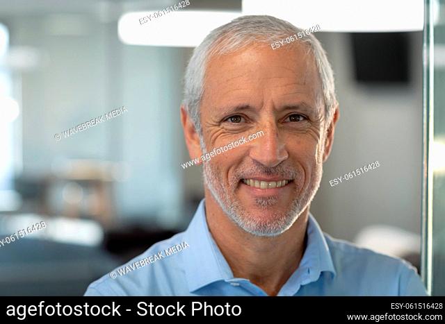 Portrait of senior businessman smiling at modern office