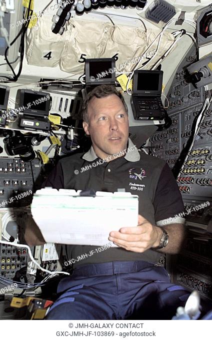 Astronaut Dominic L. Gorie, STS-108 mission commander, reads over a space walk plan on Endeavour's aft flight deck during the extravehicular activity (EVA) of...