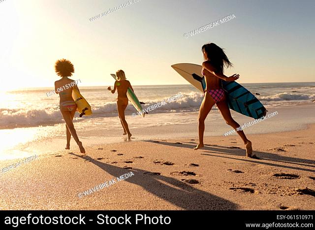 Young mixed race women holding surf boards on beach