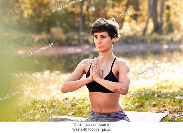 Mid adult woman in forest practicing yoga, meditation