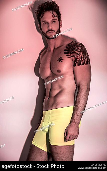 Handsome shirtless muscular man, standing, on light background in studio shot