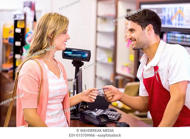 Smiling woman at cash register paying with credit card