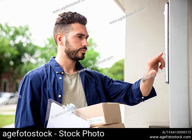 Delivery man standing in front of doorway while ringing doorbell