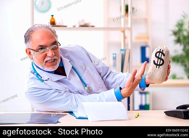 Senior male doctor holding moneybag in the hospital
