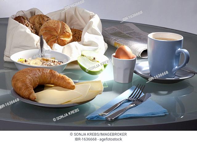 Set breakfast table with coffee, rolls, cereal, cheese, apple, egg, Bamberger Hoernla croissant and newspaper