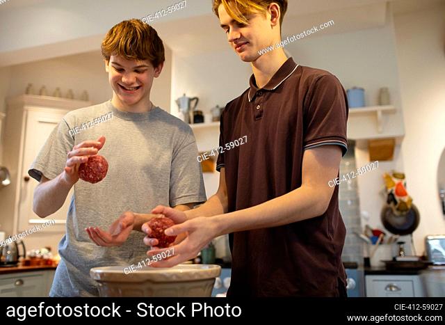 Teenage boys making hamburgers in kitchen