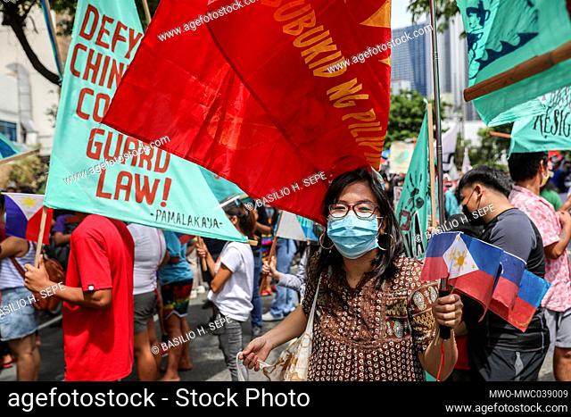 Metro Manila, Philippines. 12th June 2021. Activists carry signs and Philippine flags as they gather to protest in front of the Chinese consulate marking...