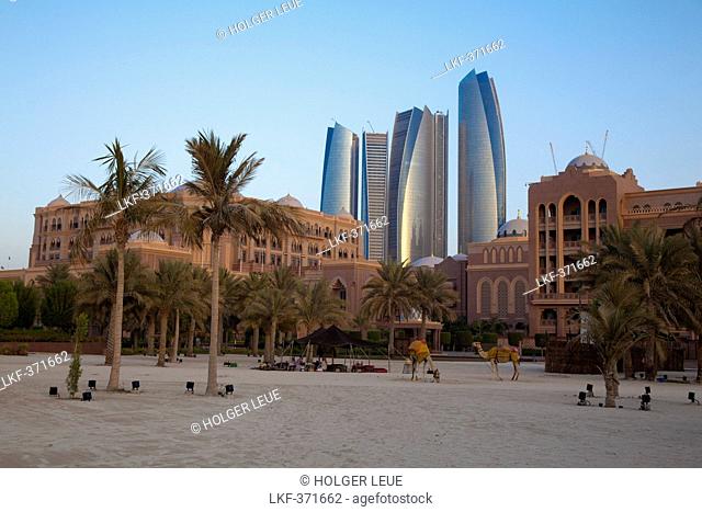 Sandy beach with palms, Emirates Palace hotel and high rise buildings, Abu Dhabi, United Arab Emirates