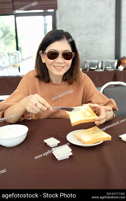 asian woman toothy smiling face with butter and bread in hand