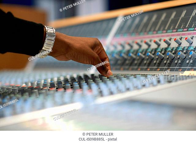 Hand of male college student at sound mixer in recording studio