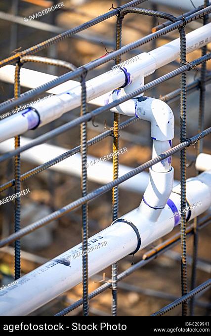 Newly installed PVC plumbing pipes and steel rebar configuration at construction site