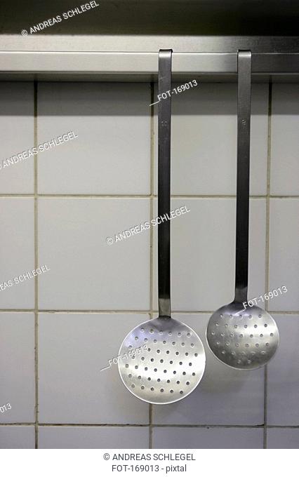 Front view of two strainers hanging in a kitchen
