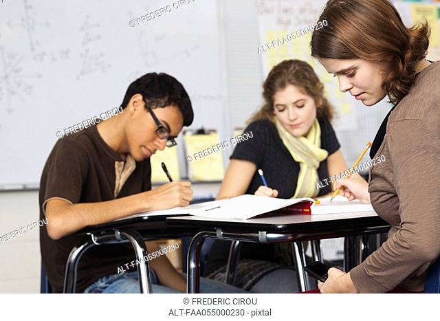Students working in class, one text messaging under her desk