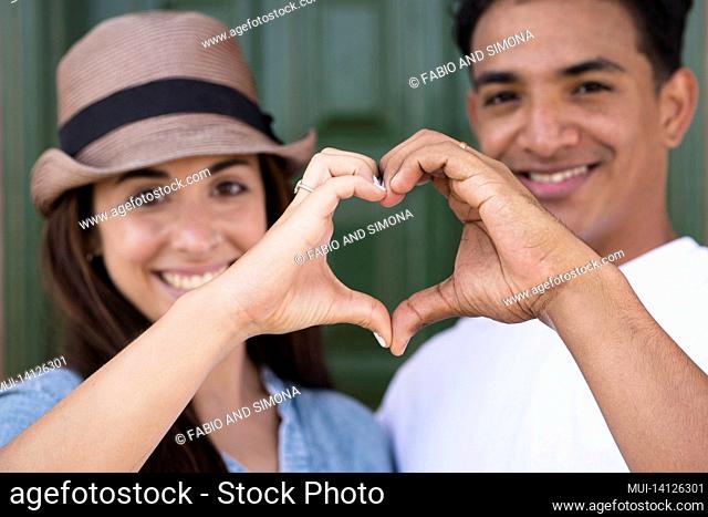 portrait of happy couple making heart shape sign with hands. happy adult couple falling in love making heart shape symbol with hands