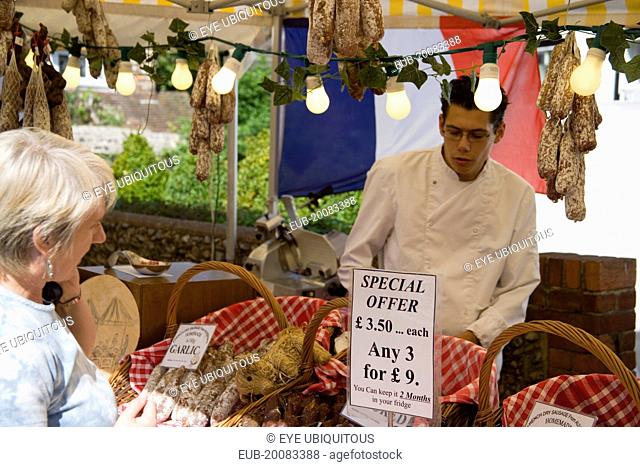 French Market. Selection of sausages on display in baskets on stall with woman purchasing from male stall holder