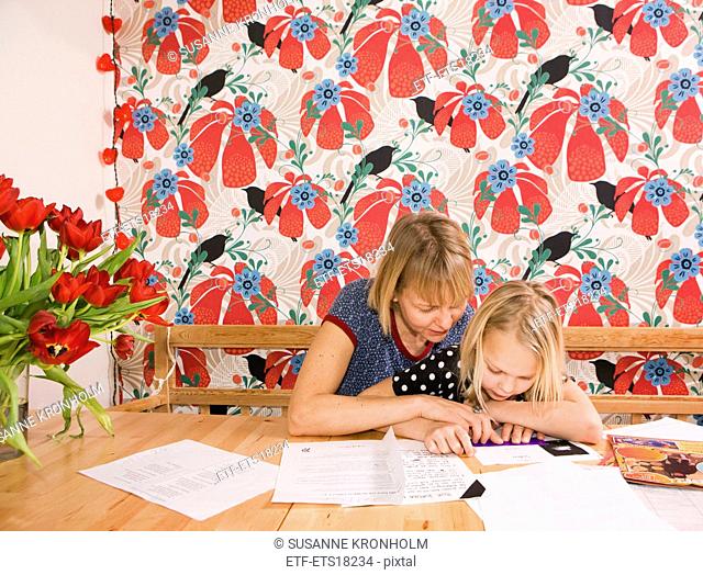 Woman helping girl with homework, Sweden