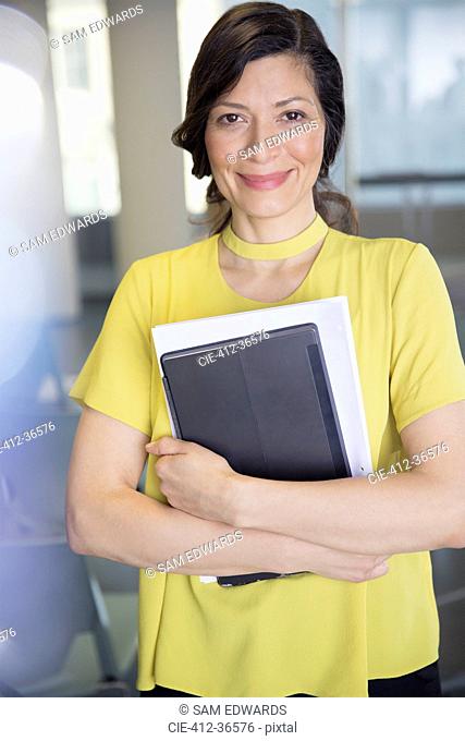 Portrait smiling, confident businesswoman with digital tablet and paperwork