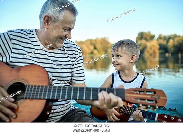 Grandfather teaching grandson playing guitar