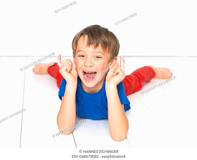 cool, six year old boy with red trousers and blue shirt on white floor