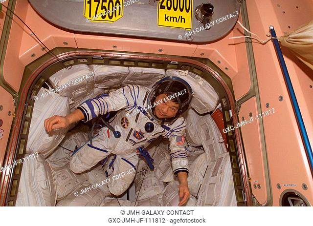 Wearing a Russian Sokol suit, astronaut Leroy Chiao, Expedition 10 commander and NASA ISS science officer, floats in a hatch in the Unity node of the...