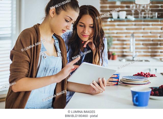 Caucasian women using digital tablet in kitchen