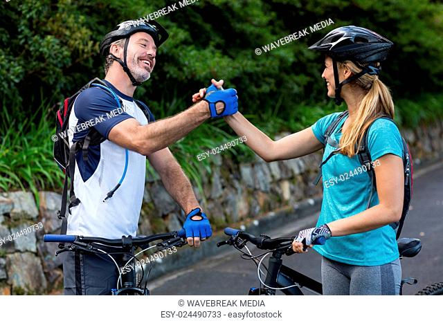 Athletic couple holding hands while riding bicycle