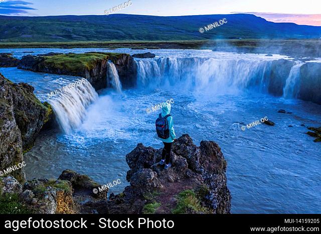 the aerial view of a woman enjoying beautiful waterfall of godafoss at sunset light. iceland in the summer season