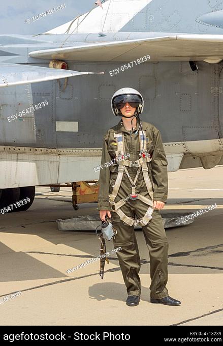 Military pilot in helmet stands near jet plane