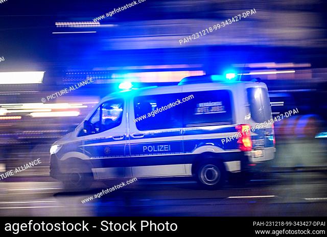 18 December 2023, Saxony, Dresden: A police car with flashing blue lights drives across the Augustus Bridge on the edge of a demonstration by the right-wing...