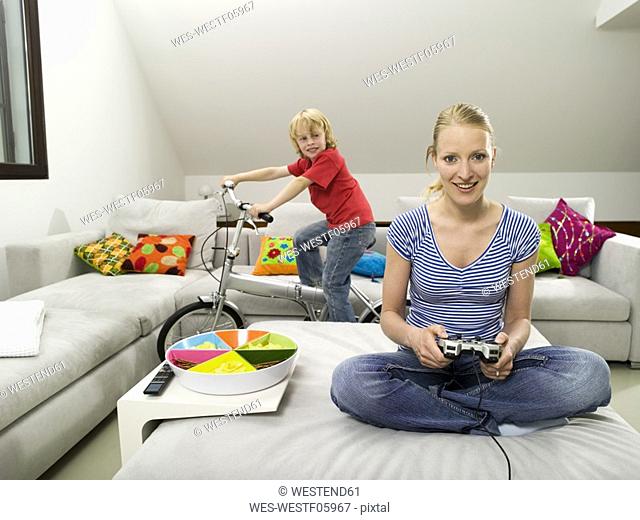 Mother and son in living room, mother playing computre game