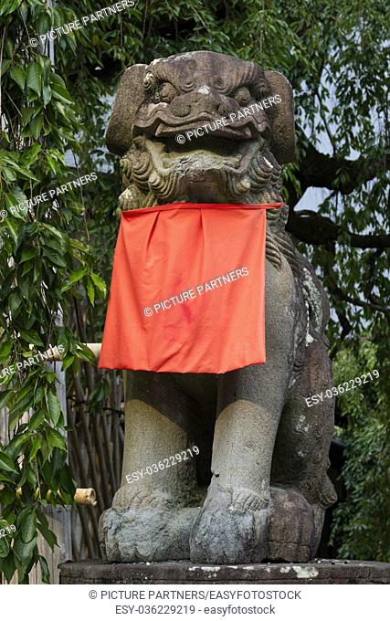 Stone guardian lion dog, Komainu, with a red skirt in Nara park