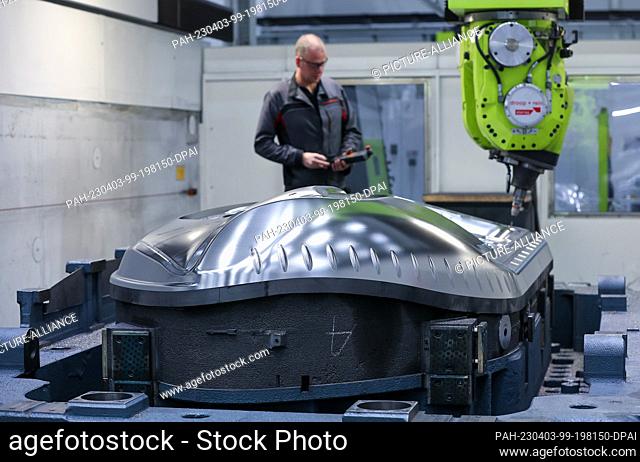 03 April 2023, Saxony, Schwarzenberg: An employee of Porsche Werkzeugbau GmbH monitors the milling and drilling work on a future tool for a Porsche side part