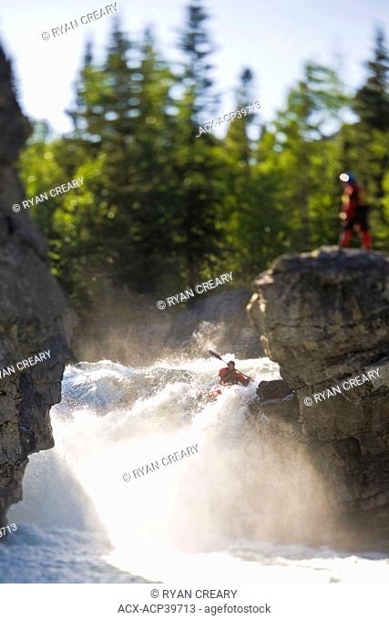 A male kayaker paddles over Elbow Falls, Elbow River, Alberta, Canada