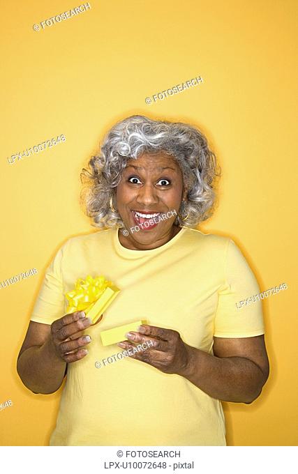 African American female mature adult opening gift box looking surprised and happy