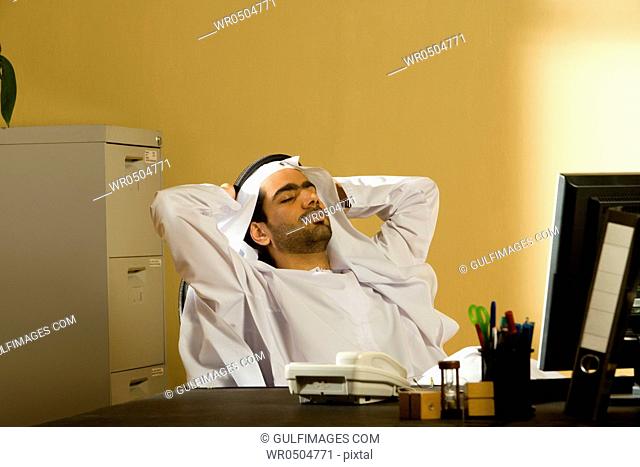Arab man sitting with hands behind head