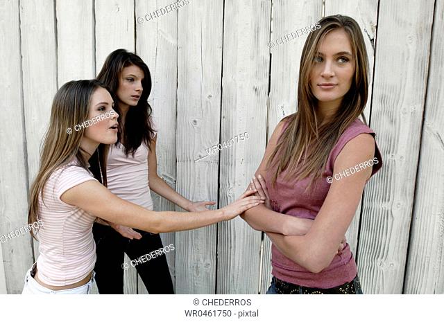 Two young women talking to another young woman standing in front of them