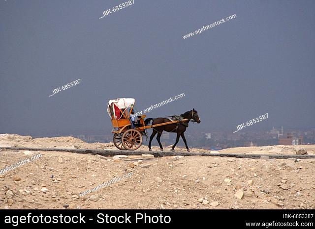 A tourist coach on its way to the Pyramid of Khufu in front of an approaching bad weather front, Cairo