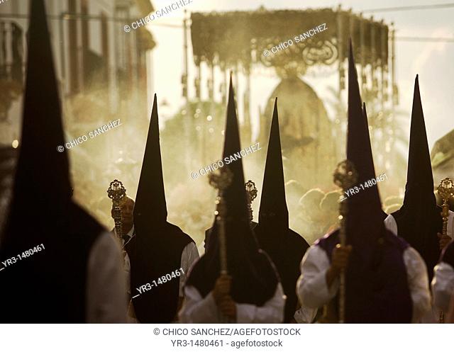 Penitents walk in front of a throne displaying a sculpture of Our Lady of Sorrows during an Easter Holy Week procession in Carmona village, Seville province