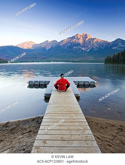 Man sitting on dock meditating at Pyramid Lake, Jasper National Park, Alberta, Canada