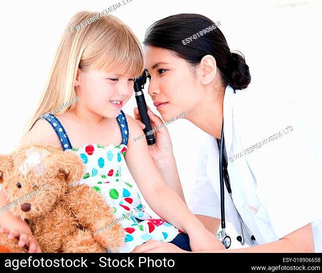 Asian doctor examining little girl with medical equipment