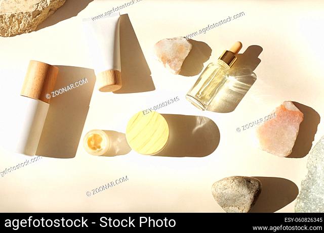 Top view of bottles of various cosmetic products placed amidst stones on white background