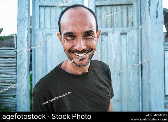 Happy mature man against wooden door at beach