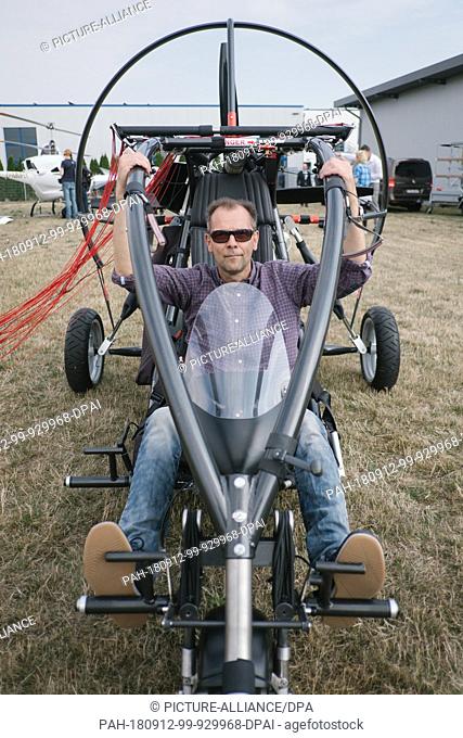 12 September 2018, Lower Saxony, Hildesheim: 12 September 2018, Germany, Hildesheim: Michael Werner sits in his three-wheeled microlight plane with paraglider