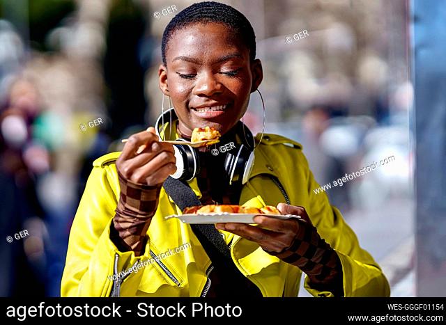 Woman holding plate eating food from spoon